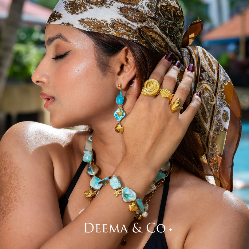 derya range - seashell necklace, bracelet and earrings with gold accents and pearl details, coral, starfish shell clam charm - 18K Gold PVD conch shell earrings with pearls by Deema & Co. on model - waterproof tarnish free and hypoallergenic