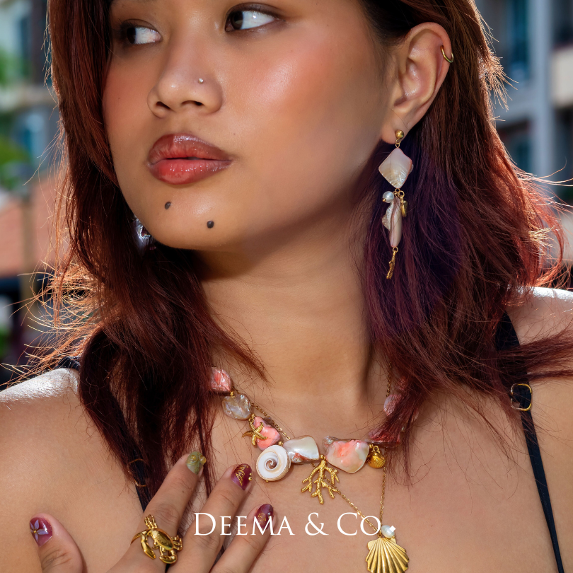 permanent dyed pink and white conch shell necklace and earrings with gold accents and pearl details, coral, starfish shell clam charm - 18K Gold PVD conch shell earrings with pearls by Deema & Co. on model - waterproof tarnish free and hypoallergenic